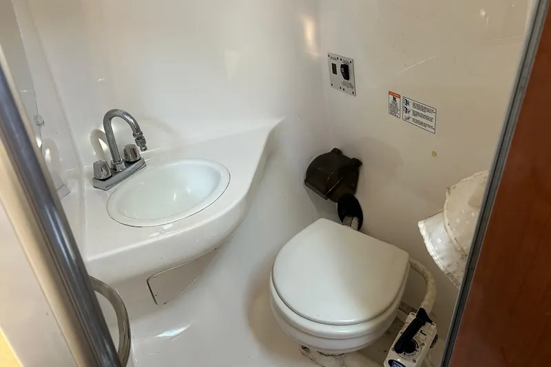 Slide: The Image of Compact bathroom in a 2001 Chaparral Signature 240 boat, featuring a sink and toilet. - 32