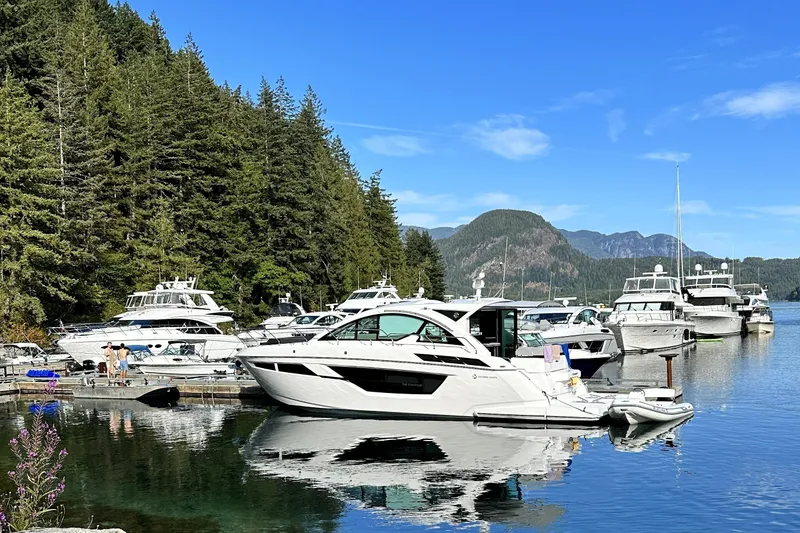 Slide: The Image of 2022 Cruisers Yachts 50 Cantius docked in scenic marina with forested backdrop. - 1
