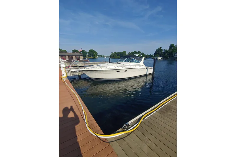 Slide: The Image of 1995 Tiara Yachts 4300 Open docked on a sunny day by the water. - 2