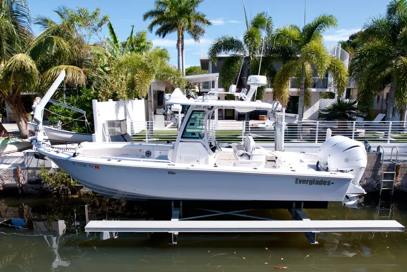 The Image of 2021 Everglades 273 Center Console boat docked near tropical palm trees. - 0