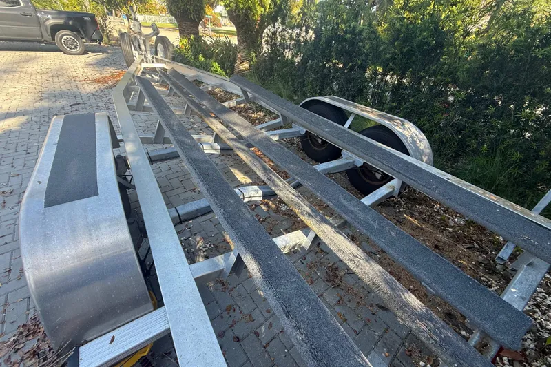 Slide: The Image of Boat trailer for 2021 Everglades 273 Center Console on paved driveway, surrounded by greenery. - 25