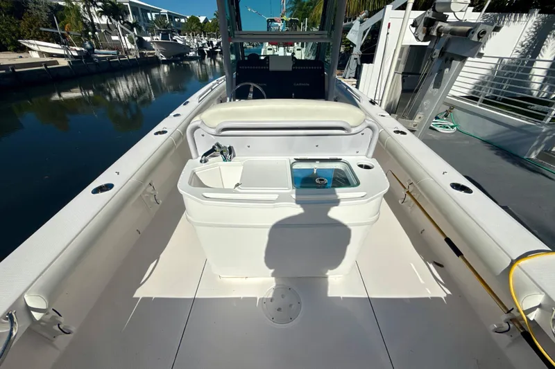 Slide: The Image of 2021 Everglades 273 Center Console boat interior with seating and storage, docked by a canal. - 7