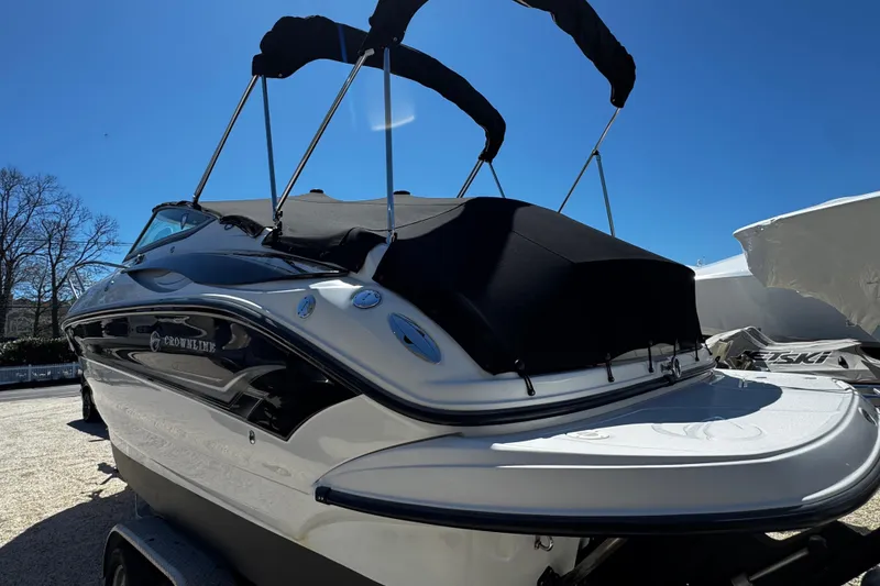 Slide: The Image of 2004 Crownline 250 CR boat with black canopy, parked on a trailer. - 12