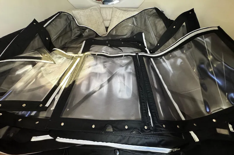 Slide: The Image of 2004 Crownline 250 CR boat with black canopy, parked outdoors under clear blue sky. - 19