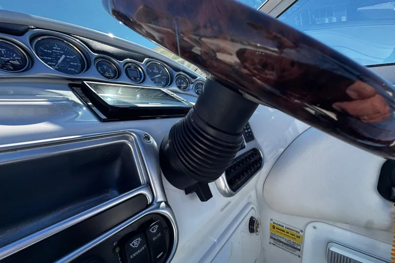 Slide: The Image of 2004 Crownline 250 CR boat interior with steering wheel and dashboard under clear blue sky. - 78