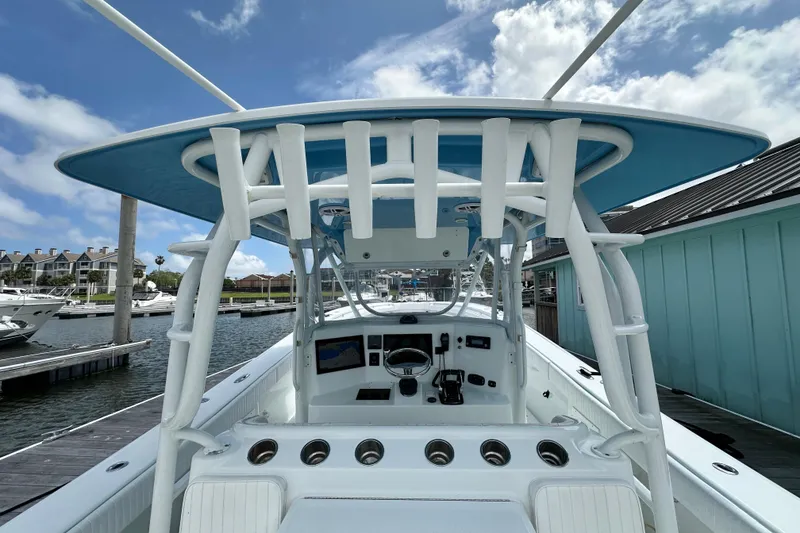 Slide: The Image of 2009 Yellowfin 42 Offshore boat at marina, showcasing helm and T-top under blue sky. - 13