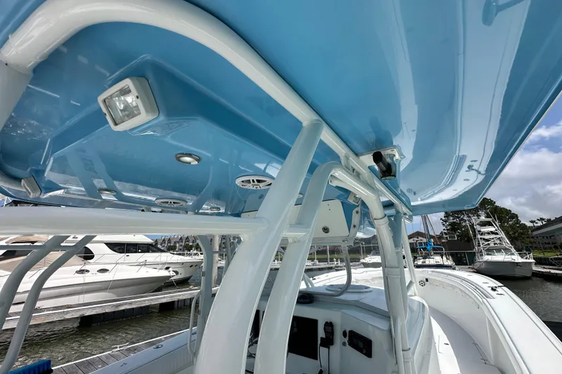 Slide: The Image of 2009 Yellowfin 42 Offshore boat interior with blue canopy and docked yachts in background. - 15