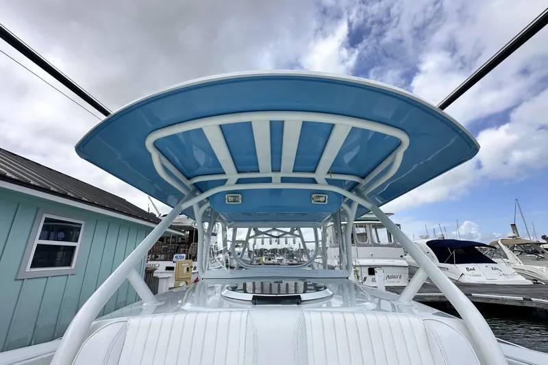 Slide: The Image of 2009 Yellowfin 42 Offshore boat with blue canopy, docked at marina under cloudy sky. - 25
