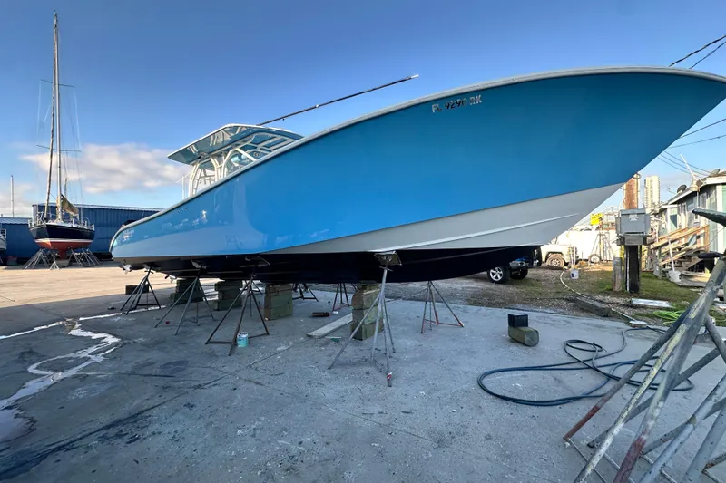 Slide: The Image of 2009 Yellowfin 42 Offshore boat in dry dock, vibrant blue hull, under maintenance. - 3