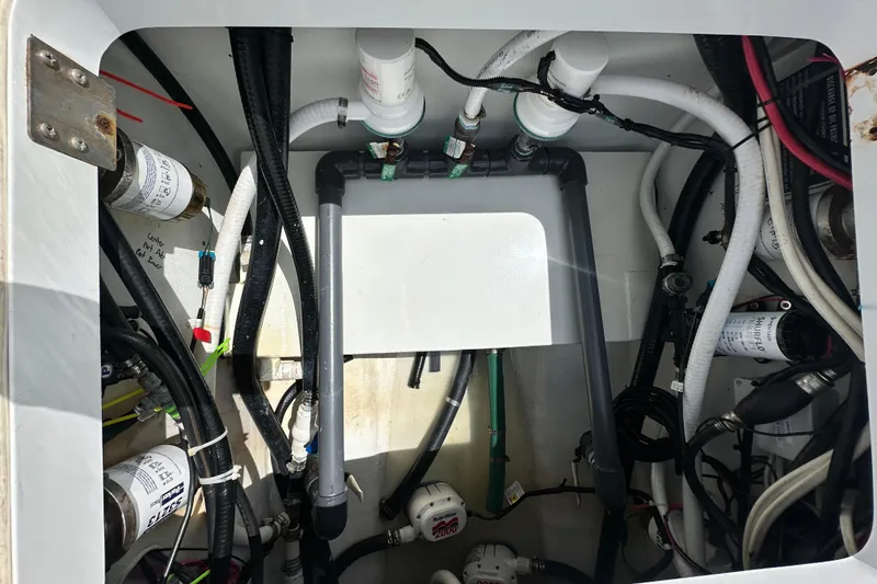 Slide: The Image of Engine compartment of a 2009 Yellowfin 42 Offshore boat, showcasing various hoses and filters. - 36