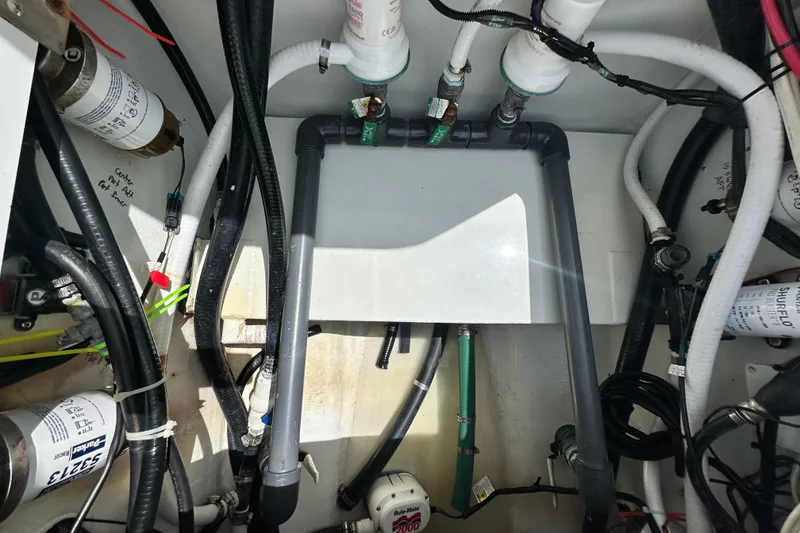 Slide: The Image of Engine compartment of a 2009 Yellowfin 42 Offshore boat, showcasing pipes and filters. - 38