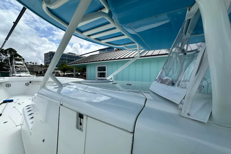 Slide: The Image of 2009 Yellowfin 42 Offshore boat with blue canopy, docked near buildings. - 39