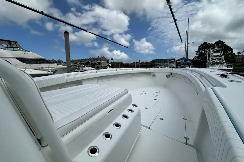 Slide: The Image of 2009 Yellowfin 42 Offshore boat docked, showcasing spacious deck and seating under a cloudy sky. - 42