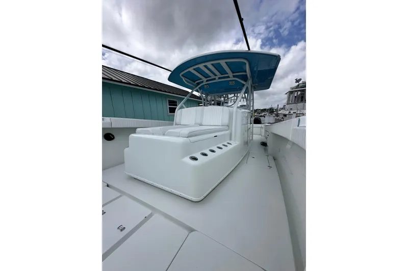 Slide: The Image of 2009 Yellowfin 42 Offshore boat with white seating and blue canopy under cloudy sky. - 58