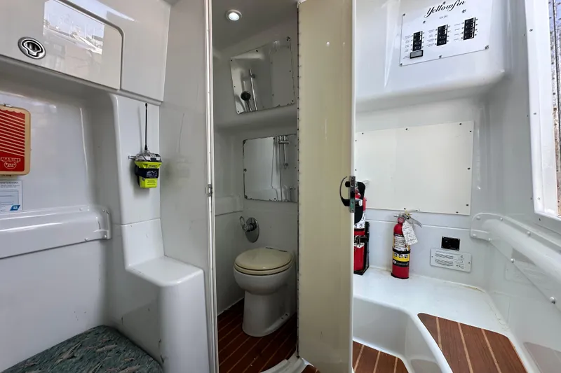 Slide: The Image of 2009 Yellowfin 42 Offshore boat interior with toilet, fire extinguishers, and control panel. - 66