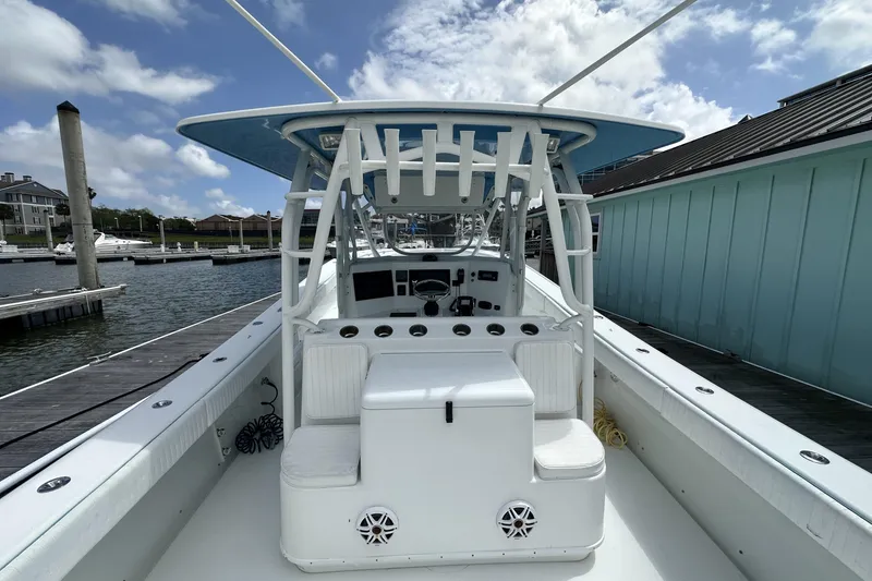 Slide: The Image of 2009 Yellowfin 42 Offshore boat docked, showcasing spacious deck and helm under blue sky. - 9