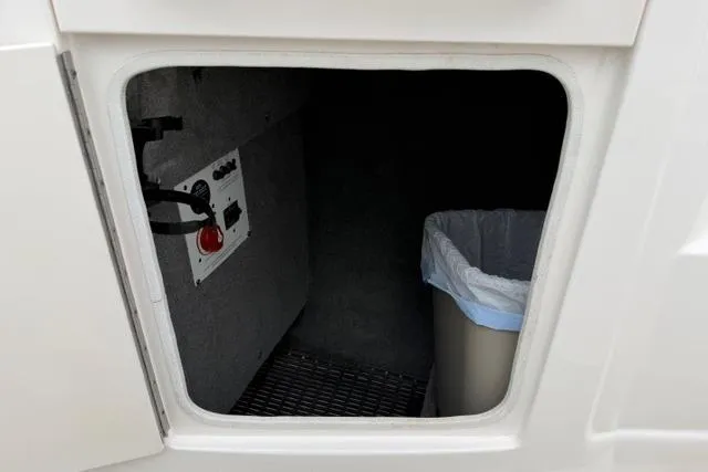 Slide: The Image of Storage compartment in a 2010 Chaparral Sunesta 244 boat, featuring a trash bin and control panel. - 17