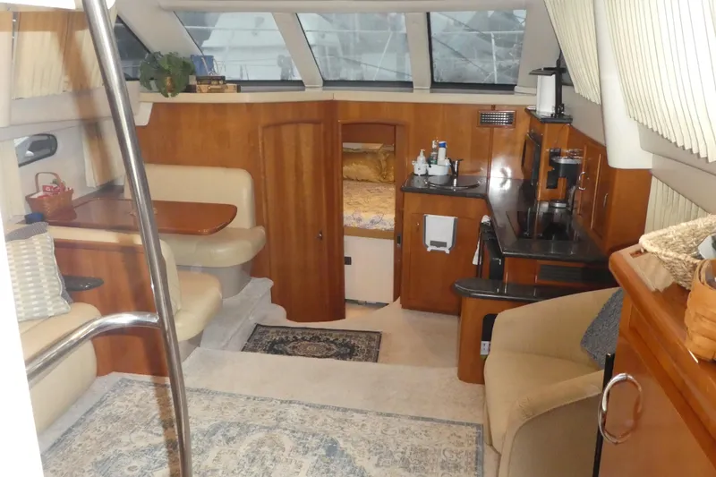 Slide: The Image of Interior of a 2006 Carver 366 Motor Yacht, featuring cozy seating and a compact kitchen area. - 11