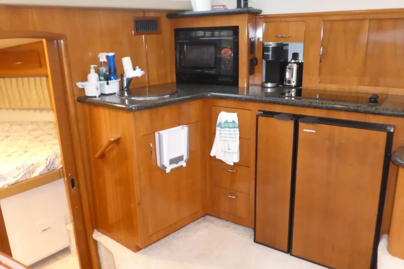 Slide: The Image of 2006 Carver 366 Motor Yacht kitchen with wood cabinetry, appliances, and compact design. - 17