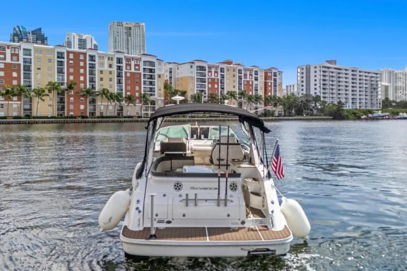 Slide: The Image of 2015 Sea Ray Sundancer 350 yacht on water, cityscape background, American flag displayed. - 4