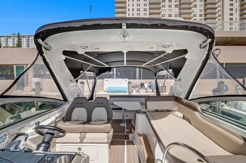 Slide: The Image of 2015 Sea Ray Sundancer 350 interior with seating and helm, docked near buildings. - 6