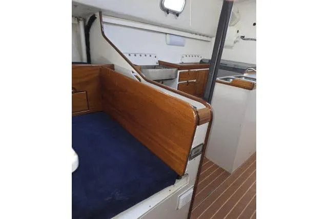 Slide: The Image of Interior of 1986 Bill Lee Yachts Santa Cruz 50, featuring wood accents and compact kitchen area. - 10