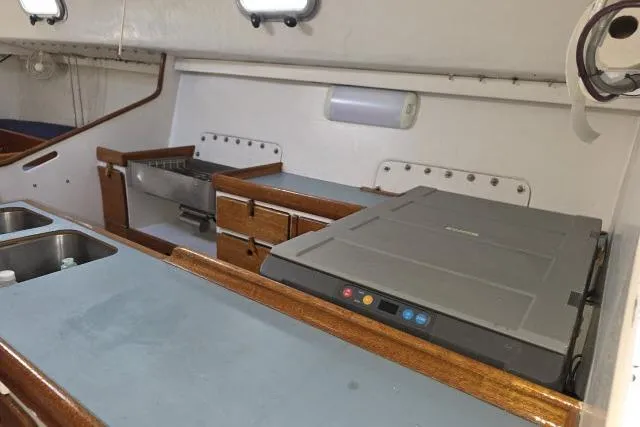 Slide: The Image of Interior of 1986 Bill Lee Yachts Santa Cruz 50, featuring a compact galley kitchen. - 14