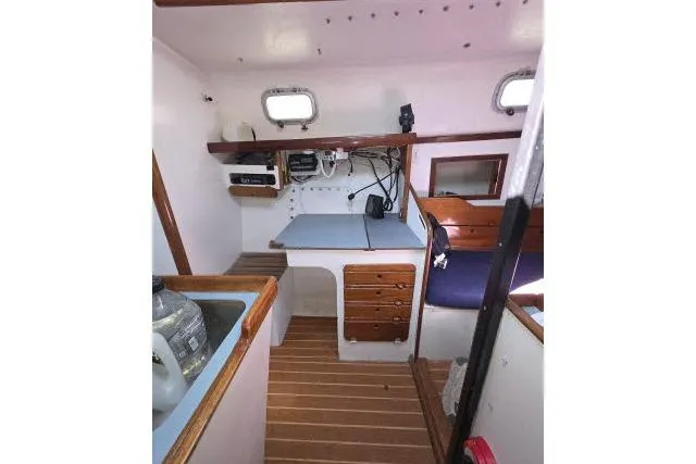 Slide: The Image of Interior of 1986 Bill Lee Yachts Santa Cruz 50, featuring compact navigation station and wooden flooring. - 15