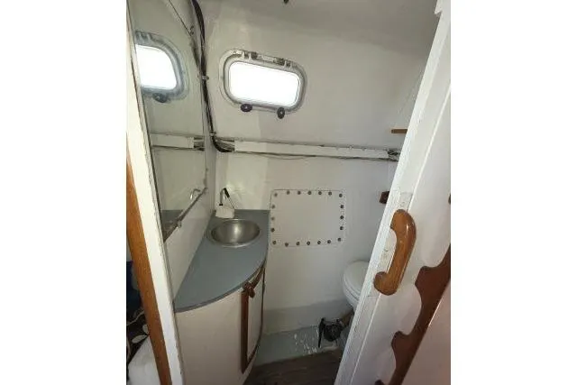 Slide: The Image of 1986 Bill Lee Yachts Santa Cruz 50 bathroom interior with sink and porthole. - 25