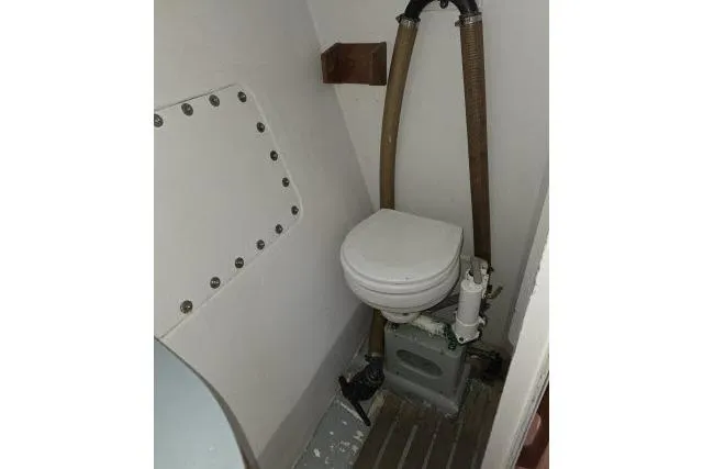 Slide: The Image of 1986 Bill Lee Yachts Santa Cruz 50 marine toilet with plumbing and compact design. - 28