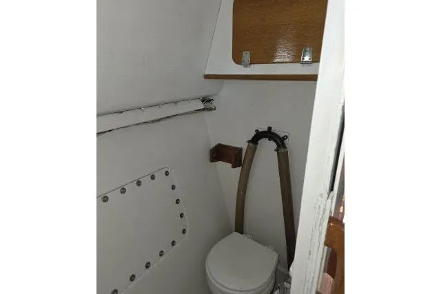 Slide: The Image of 1986 Bill Lee Yachts Santa Cruz 50 bathroom interior with compact toilet and storage shelf. - 29