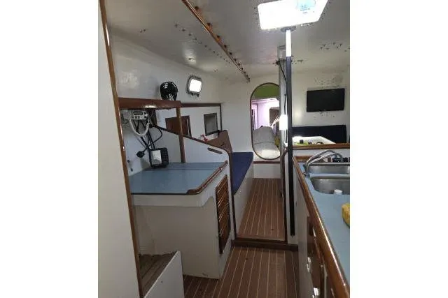 Slide: The Image of Interior of 1986 Bill Lee Yachts Santa Cruz 50, featuring a compact kitchen and seating area. - 3