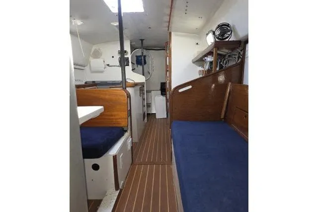 Slide: The Image of Interior of 1986 Bill Lee Yachts Santa Cruz 50, featuring wooden finishes and blue seating. - 5