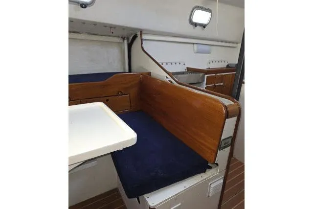 Slide: The Image of Interior of 1986 Bill Lee Yachts Santa Cruz 50 with wooden accents and blue cushions. - 6