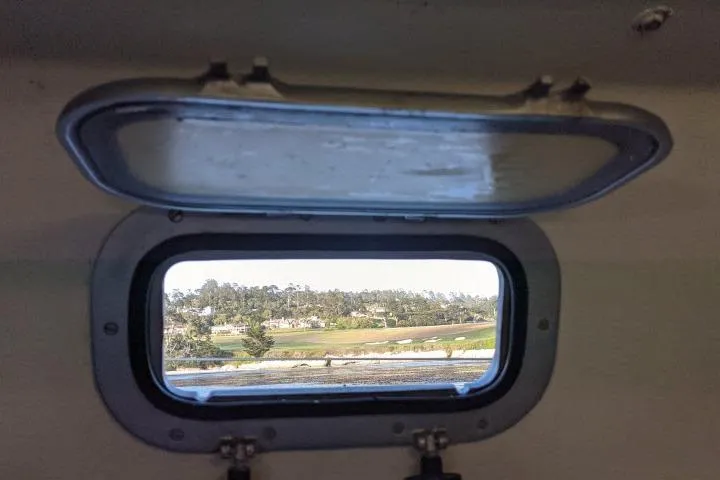 Slide: The Image of Open porthole view from 1986 Bill Lee Yachts Santa Cruz 50, showcasing scenic landscape. - 9