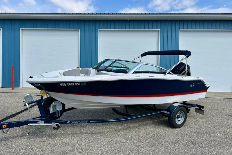 Slide: The Image of 2017 Four Winns 180 Horizon boat on trailer, parked in front of blue garage doors. - 1
