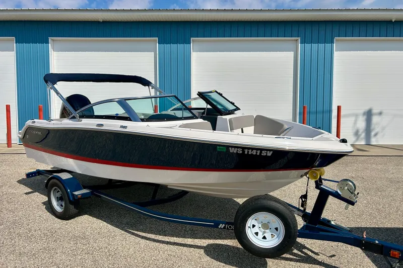 Slide: The Image of 2017 Four Winns 180 Horizon boat on trailer, parked in front of blue garage doors. - 2