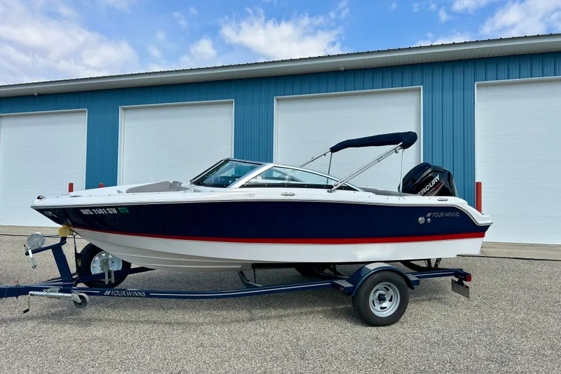 Slide: The Image of 2017 Four Winns 180 Horizon boat on trailer, parked outside blue building. - 3