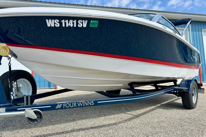 Slide: The Image of 2017 Four Winns 180 Horizon boat on trailer, blue and white design, parked outdoors. - 6