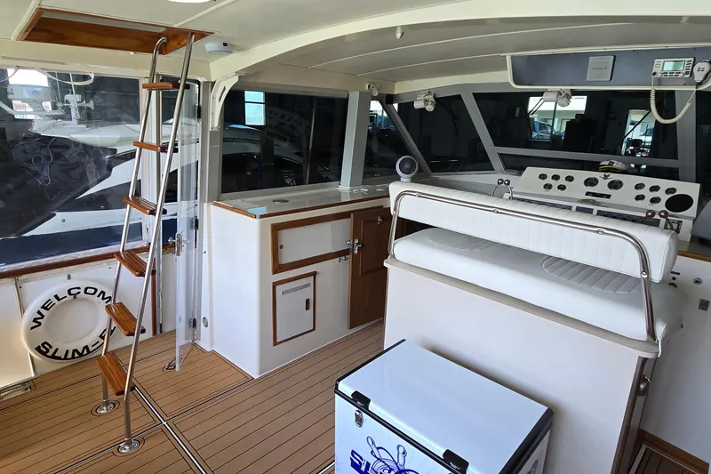Slide: The Image of 1977 Bertram 42 Flybridge Motor Yacht interior with helm, seating, and wooden ladder. - 14