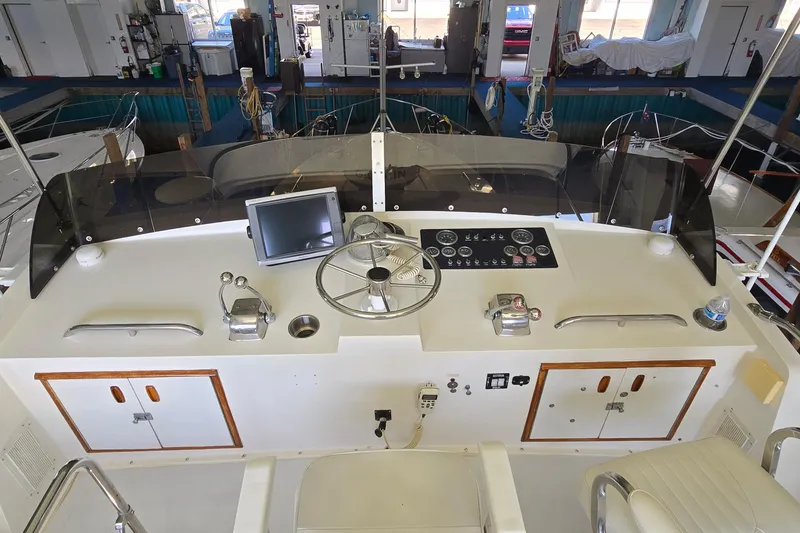 Slide: The Image of 1977 Bertram 42 Flybridge Motor Yacht helm with steering wheel, controls, and navigation screen. - 15