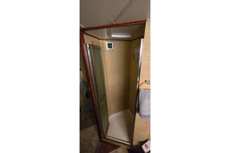 Slide: The Image of Shower area inside a 1977 Bertram 42 Flybridge Motor Yacht, featuring a glass door and towel rack. - 37