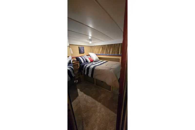 Slide: The Image of Cozy bedroom interior of 1977 Bertram 42 Flybridge Motor Yacht with striped bedding. - 38