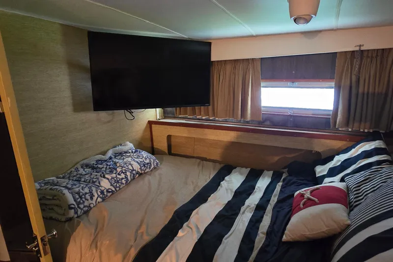 Slide: The Image of Cozy bedroom in 1977 Bertram 42 Flybridge Motor Yacht with striped bedding and wall-mounted TV. - 39
