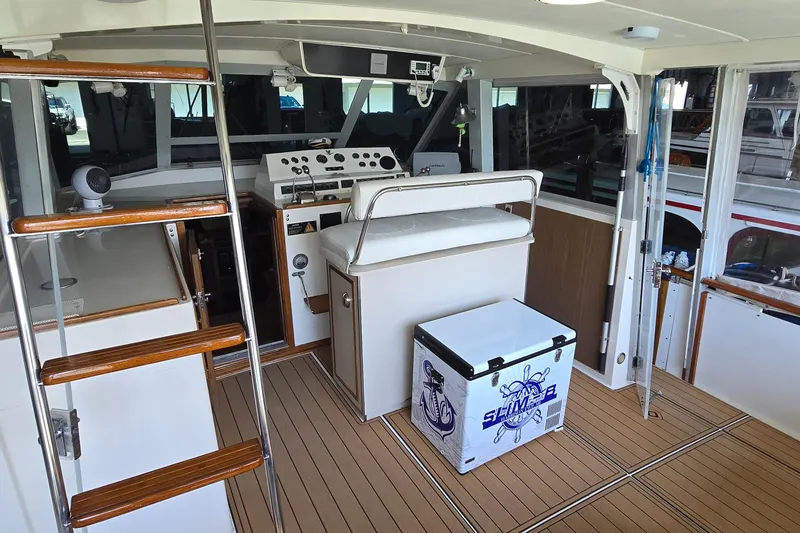 Slide: The Image of 1977 Bertram 42 Flybridge Motor Yacht interior with helm, seating, and cooler on teak deck. - 7