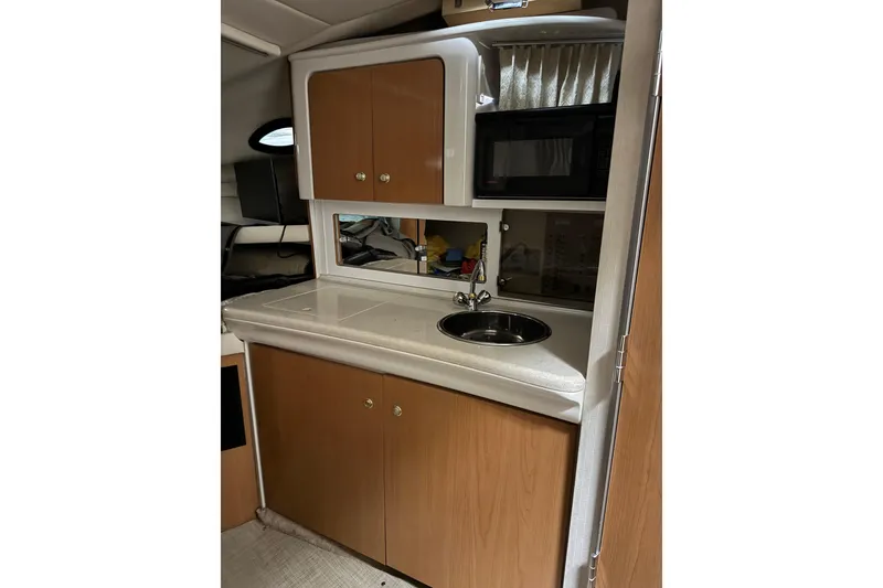 Slide: The Image of 2001 Regal Commodore 2760 boat kitchenette with sink, microwave, and wooden cabinets. - 14