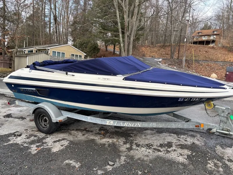 Slide: The Image of 2011 Larson 850 boat on trailer parked in wooded area. - 15