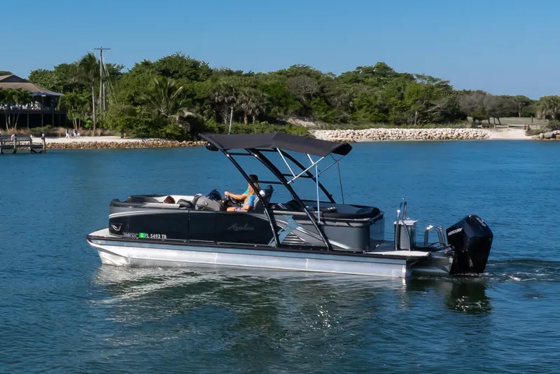 The Image of 2021 Avalon LSZ Quad Lounger 24' pontoon boat cruising on a scenic waterway. - 0
