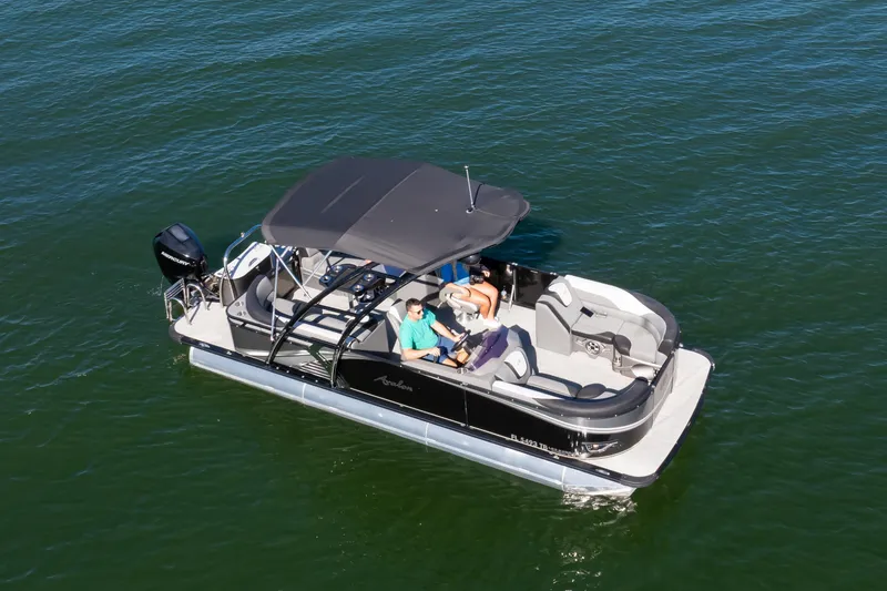 Slide: The Image of 2021 Avalon LSZ Quad Lounger 24' pontoon boat on calm water, featuring a sleek design. - 10