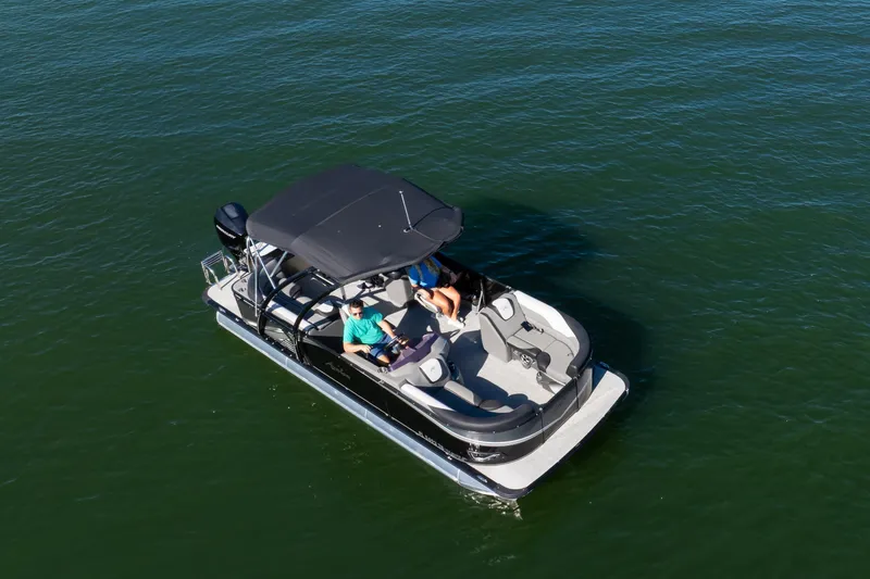 Slide: The Image of 2021 Avalon LSZ Quad Lounger 24' pontoon boat on calm water, featuring a sleek design. - 11
